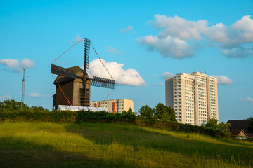 Beautiful landscape featuring a historic windmill near modern high-rise buildings, surrounded by...
