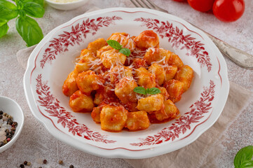 Traditional potato gnocchi with tomato sauce, parmesan cheese and fresh basil on a plate on a...
