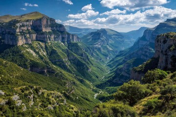 A deep green canyon with dramatic rock formations under a blue sky with scattered clouds