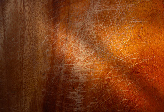 Texture of an old, reddish-brown wooden surface with many scratches. A rustic, warm background showing the patina of time and use