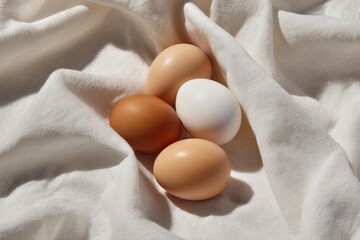 Four eggs one white amidst folds of a white cloth