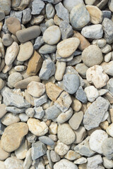 Collection of natural river stones and rocks in various shades of grey and beige, forming a textured background, suitable for landscaping companies, construction material suppliers, and garden design