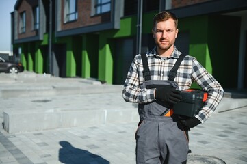 Master on call. A plumber or builder is standing near a house.