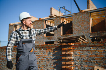 Installing brick wall. Construction worker in uniform and safety equipment have job on building