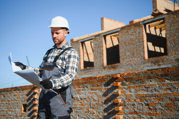 Portrait of a builder in the process of working on a construction site outdoors