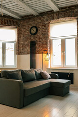 Cozy living room with gray sectional sofa, industrial brick walls, modern floor lamp, large...