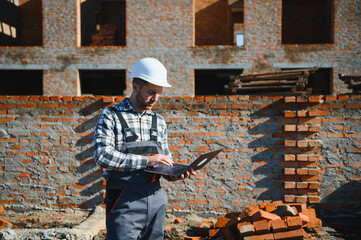 Portrait of a builder in the process of working on a construction site outdoors