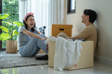 An Asian couple experiences joy as they carry boxes and arrange their new residence.

