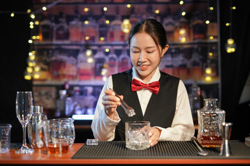 Professional female bartender preparing alcoholic drinks in a bar