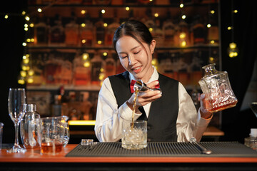 Professional female bartender preparing alcoholic drinks in a bar