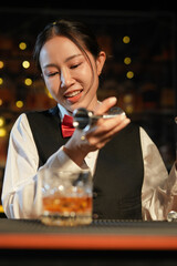 Professional female bartender preparing alcoholic drinks in a bar