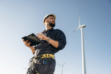 Internet connection concept, with tablet. Engineer in field checking on wind turbine production