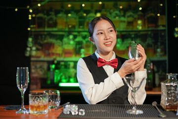 Professional female bartender preparing alcoholic drinks in a bar