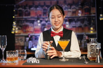 Professional female bartender preparing alcoholic drinks in a bar