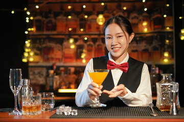 Professional female bartender preparing alcoholic drinks in a bar