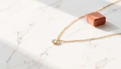 Elegant gold necklace with a sparkling pendant resting on a marble surface in soft sunlight