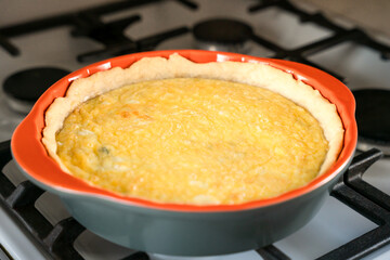 Freshly baked hot aromatic Quiche Lorraine with spinach and cheese on the stove in the kitchen. Close-up. Selective focus.