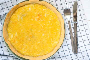 Delicious homemade Quiche Lorraine with spinach and cheese on a checkered kitchen towel. Close-up. Top view.