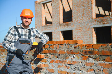 Portrait of a builder in the process of working on a construction site outdoors