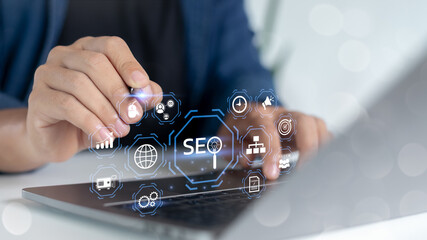 Close-up of a hand working on a laptop with SEO icons and digital marketing elements, representing...