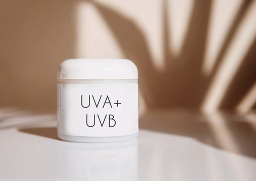 Sunscreen Tube with UVA and UVB Protection in jar on white table with sun light and shadow