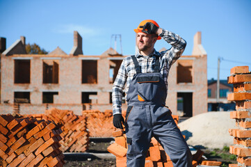 Bricklayer industrial worker installing brick masonry on exterior wall with trowel putty knife