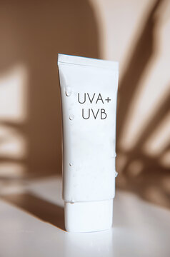 Sunscreen Tube with UVA and UVB Protection in jar on white table with sun light and shadow
