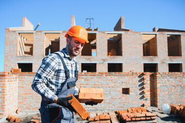 Bricklayer industrial worker installing brick masonry on exterior wall with trowel putty knife