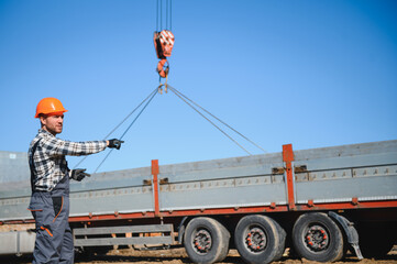 The builder controls the unloading of the panels for the roof of the house with a crane