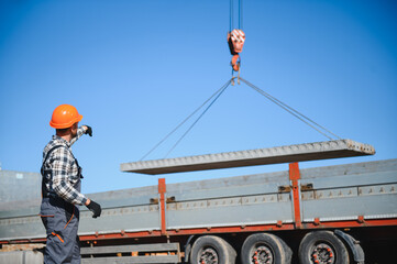 The builder controls the unloading of the panels for the roof of the house with a crane