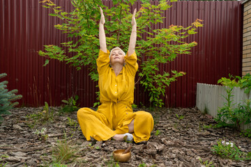 Senior Woman Enjoy serene meditation in nature, wearing yellow amidst lush greenery, connecting deeply with it