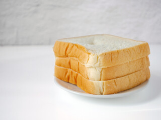 White sliced bread stacked on the white wooden table