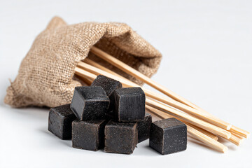 a bag of black cubes and chopsticks on a white surface