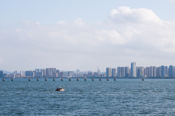Scenic View of a City Skyline Against a Calm Body of Water with a Small Boat in the Foreground and...