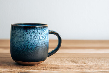 a blue coffee cup sitting on a wooden table
