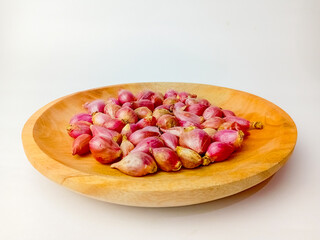 Red onions on wooden plate, isolated on white background.