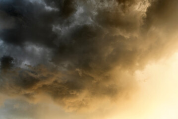 Dramatic cloudy sky with golden sunlight breaking through dark storm clouds du sunset, creating a...