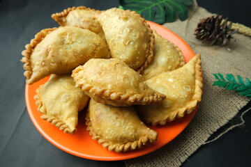 A plate full of crispy Indonesian pastel or Makassar-style jalangkote pastries, deep-fried and typically filled with vegetables or meat.