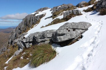 Rocky mountain slope with snow and footprints