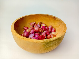 Shallots in a wooden bowl, isolated on a white background.