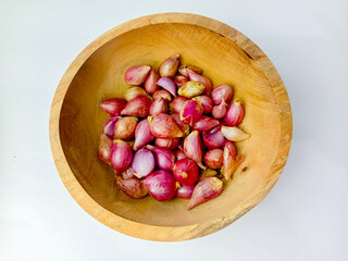 Shallots in a wooden bowl, isolated on a white background.