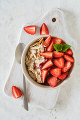 Oatmeal bowl with fresh strawberries, healthy breakfast meal