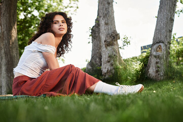 Young woman enjoys a sunny day outdoors in a stylish summer outfit by the trees