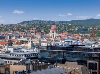 Panoramic view of Budapest with the iconic Hungarian Parliament and Buda Hills, captured from the observation deck of St. Stephen’s Basilica on a clear summer day.