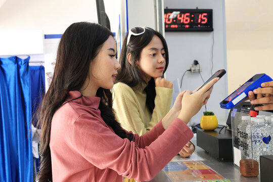 Two Female Asian Friends Paying with QRIS Barcode