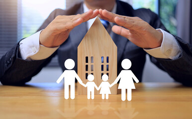 House insurance concept with businessman show protection wooden house and family icon standing in...