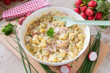 Healthy potato salad with yoghurt dressing, chives, red redish, onions and pickles in a bowl