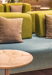 Close-up of a modern lounge setting featuring green armchairs with throw pillows. Welcoming atmosphere ideal for commercial and interior design use. Selective focus.