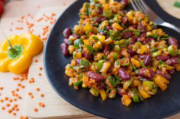 Delicious vegan salad with red lentils, kidney beans and yellow bell peppers on a plate