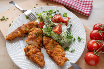 Small chicken schnitzel fresh and homemade cooked with a fresh salad on a plate